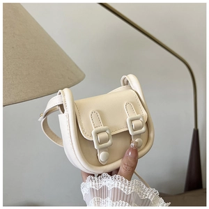 Gros plan d'un mini sac à bandoulière en cuir blanc crème avec deux boucles décoratives
