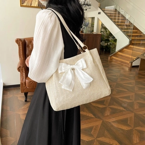 Grand sac cabas en paille tressée beige orné d'un grand nœud décoratif en satin blanc