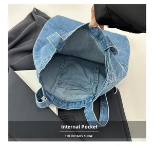 Detail view showing internal pocket and texture of the blue denim tote bag