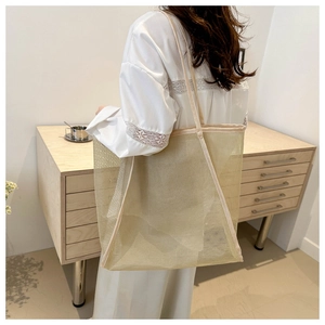 Détail d'un grand sac fourre-tout beige en maille montrant la texture et la capacité