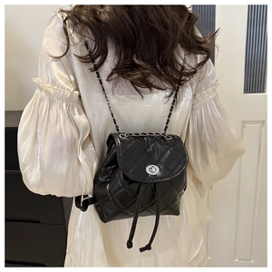 Detailed view of black quilted mini backpack with silver twist lock and chain straps
