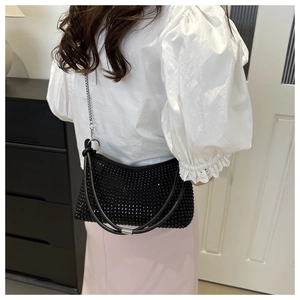 Detailed view of black rhinestone underarm bag with silver chain strap on model