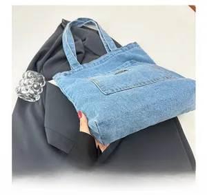 Detail of light blue denim tote bag base with front pocket and brand label