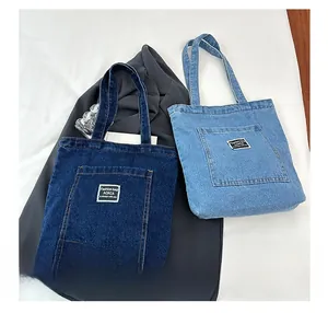 Detail of denim tote bags with contrast stitching and woven label in blue shades