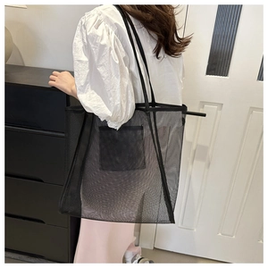 Détail d'un sac cabas en filet noir montrant la texture semi-transparente et la poche plate