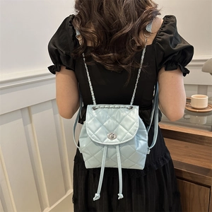 Mini light blue quilted backpack with silver chain straps worn by a female model