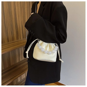 Détail du sac seau crème avec grande poignée en perles blanches et chaîne argentée