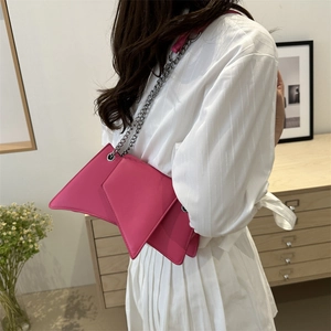 Sac bandoulière géométrique rose vif avec chaîne argentée porté par un mannequin