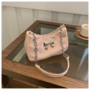 Close-up of pink shoulder bag featuring a silver metal bow and chunky chain strap
