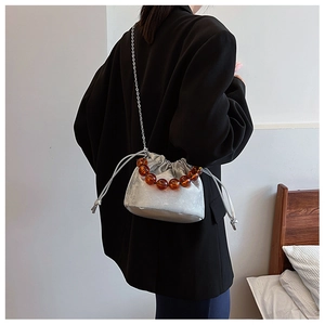 Détail du sac seau argenté à cordon avec poignée en perles d'ambre et bandoulière