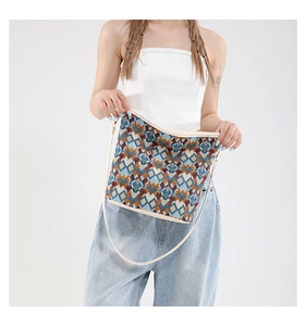 Vue détaillée du motif géométrique tissé coloré et des bords en cuir beige du sac seau