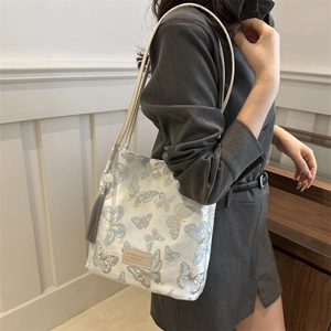 Grand sac cabas beige avec broderie papillon bleue et pompon gris décoratif