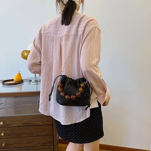 Sac seau noir à cordon avec poignée en perles ambrées et bandoulière en chaîne fine