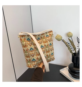 Détail du sac seau en jacquard géométrique avec bandoulière blanche et décor floral