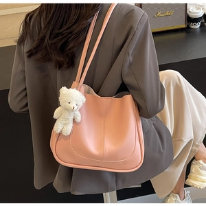 Sac seau rose en cuir mat avec breloque ours blanc porté par un mannequin de mode