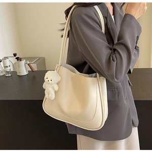 Vue détaillée du grand sac cabas beige en cuir avec surpiqûres et pendentif ours
