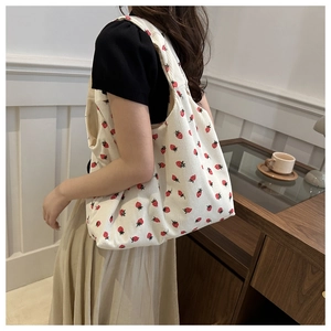 Detail of white corduroy tote bag with red strawberry print showing textured fabric
