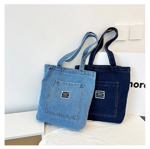 Detail of light and dark blue denim tote bags featuring front pockets and white logo labels