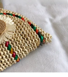 Détail d'un sac en paille tissé à la main avec bords colorés et une grande fleur crème