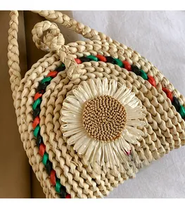 Vue détaillée du sac en paille tressée beige avec bordures colorées et décor de marguerite