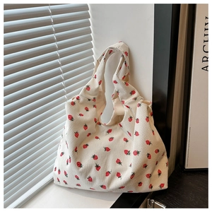 Detailed close-up of white corduroy tote bag featuring red strawberry print pattern