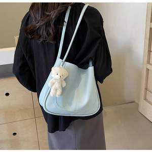 Détail du sac seau bleu clair en cuir avec un ours en peluche blanc et couture de style