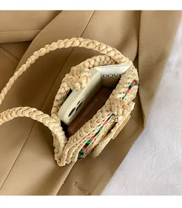 Détail du sac en paille tressée montrant l'intérieur spacieux et la poignée tressée