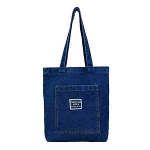 Classic dark blue denim tote bag with long shoulder straps and front patch pocket