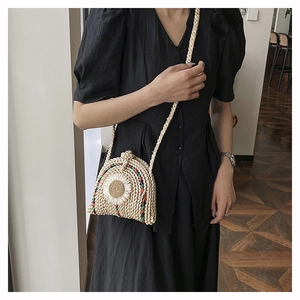 Sac bandoulière en paille tressée avec détail tournesol 3D porté par un mannequin