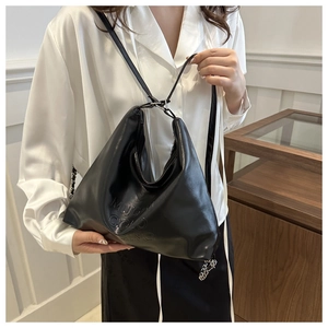 Dettaglio della borsa Hobo in pelle PU nera con eleganti lettere a rilievo e finitura lucida