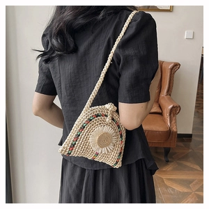 Détail d'un sac en paille tressée avec grande marguerite 3D et bandoulière en corde tressée
