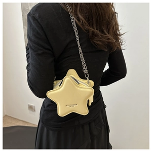 Détail d'un sac bandoulière jaune en forme d'étoile avec chaîne en argent sur un mannequin