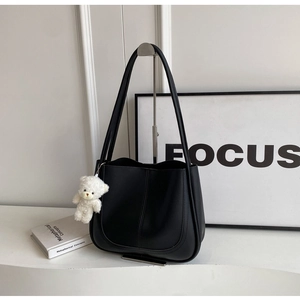 Détail d'un sac seau structuré en simili cuir noir avec un pendentif d'ours blanc mignon