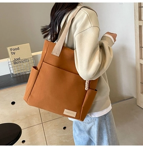 Detail view of brown canvas tote bag featuring reinforced straps and side storage pockets