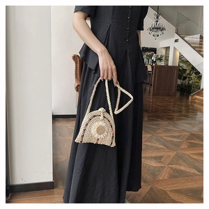 Détail d'un sac à main tissé avec des marguerites blanches et bandoulière longue