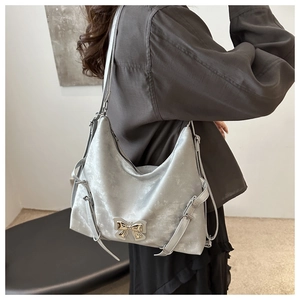 Détail du sac bandoulière en daim gris argenté avec nœud métallique et boucles latérales