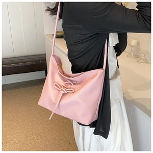Gros plan d'un sac à bandoulière rose en cuir avec un nœud décoratif et texture douce
