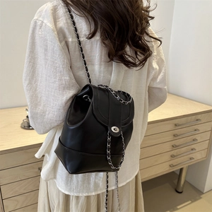 Sac à dos seau en cuir noir minimaliste avec chaînes argentées porté par un modèle