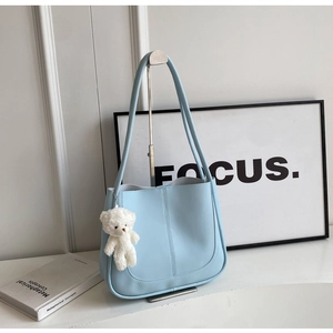 Détail du sac à bandoulière bleu clair avec surpiqûres en U et charmant petit ours blanc