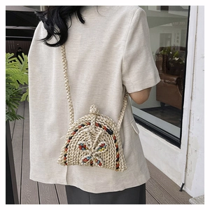 Détail du sac en paille tissé à la main avec broderie papillon colorée et bandoulière tressée