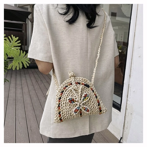 Détail du sac coquillage en paille tressée avec nœuds colorés et bandoulière longue