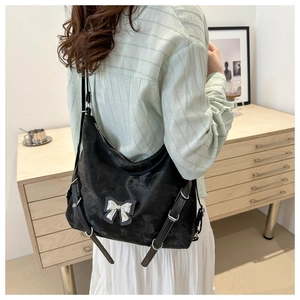 Détail du sac bandoulière noir avec nœud argenté et boucles en décor intérieur