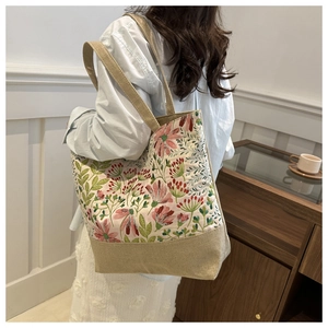 Detail of floral tote bag with natural linen base shown on shoulder for size context