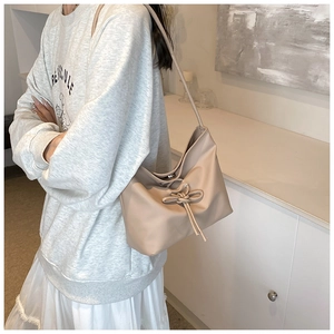 Détail du sac seau beige élégant avec nœud à cordon et finition en similicuir minimaliste