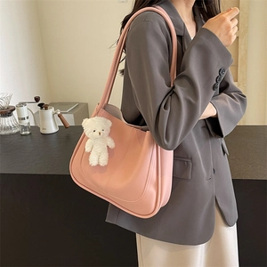 Sac à bandoulière rose en similicuir avec pendentif ours porté par un mannequin