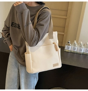 Detail view of cream canvas tote bag with brown straps and functional front pocket