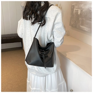 Détail du sac cabas nœud en cuir noir porté à l'épaule d'un mannequin pour voir la taille