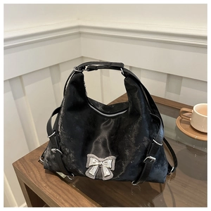 Détail du sac noir avec un nœud en métal argenté et des cordons de serrage latéraux réglables