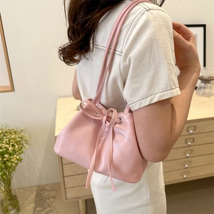 Pink matte leather bucket bag with bow detail shown by model for chic daily style