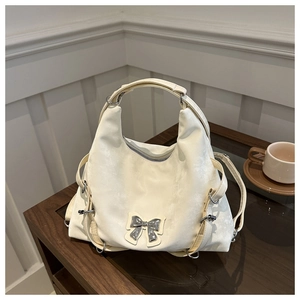 Détail du sac en cuir blanc cassé avec nœud argenté et anneaux métalliques